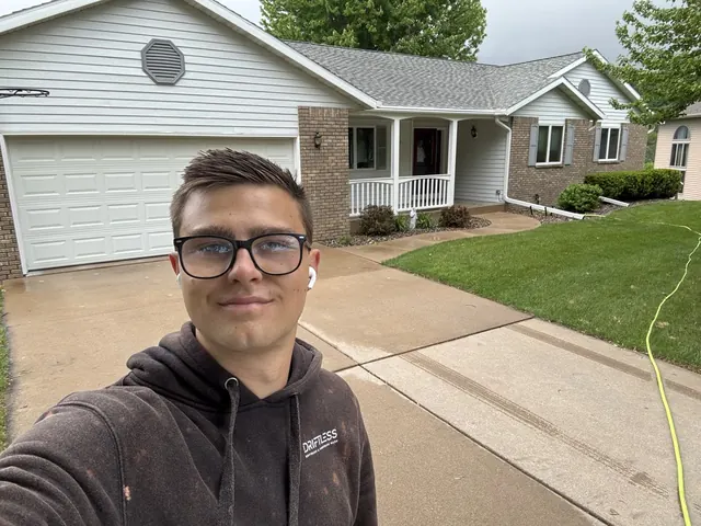 Mikoda, owner of Driftless Softwash, in front of a house he washed