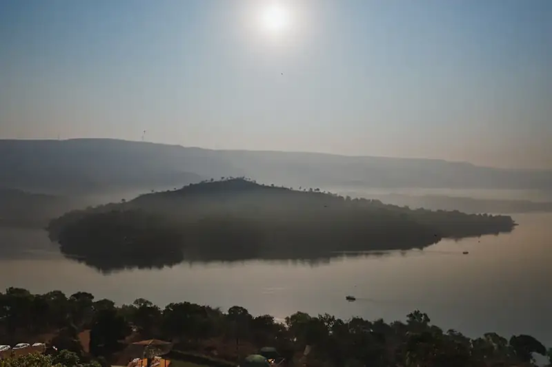 Fog lifting off a wooded island in still water at sunrise