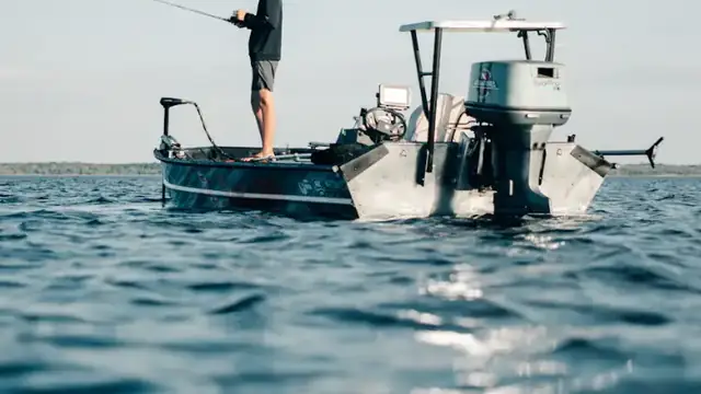 An angler standing on the bow of a small boat on wide open water