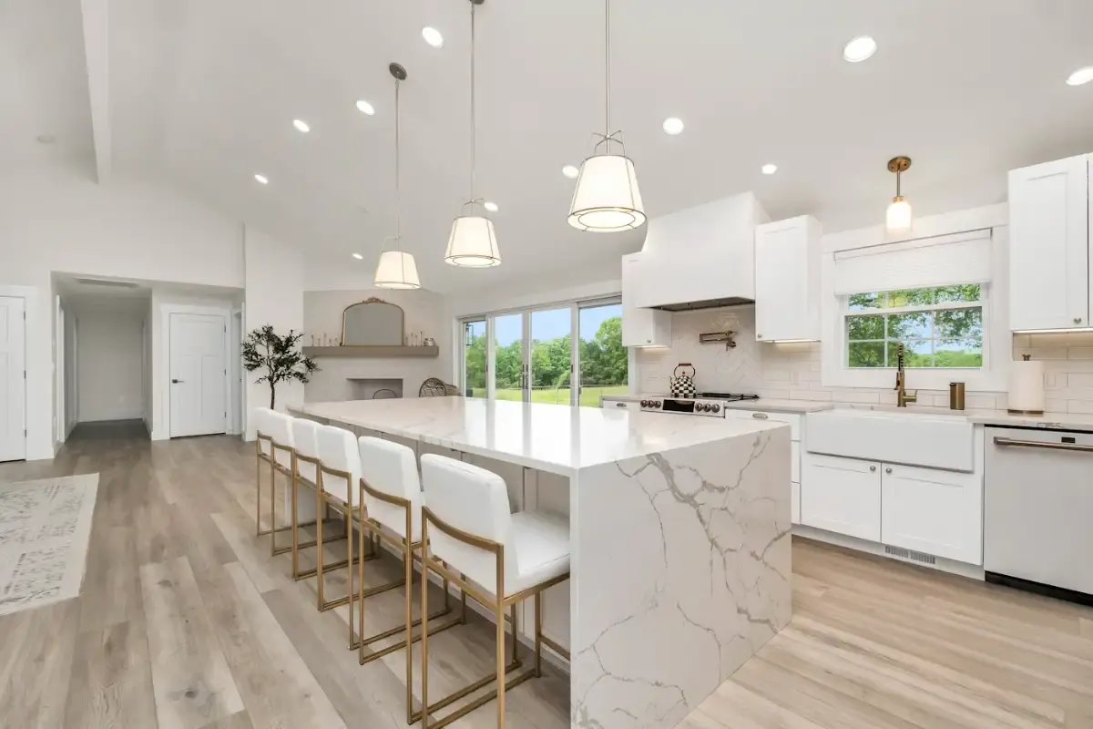 Kitchen with a long marble-look island, four stools, pendant lights and white cabinets