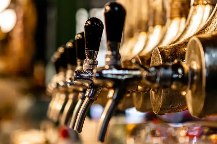 A row of chrome beer taps with black handles along the back bar
