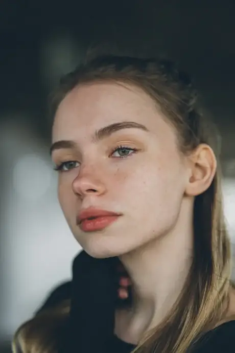 A young woman with her hair tied back, looking calmly toward the camera