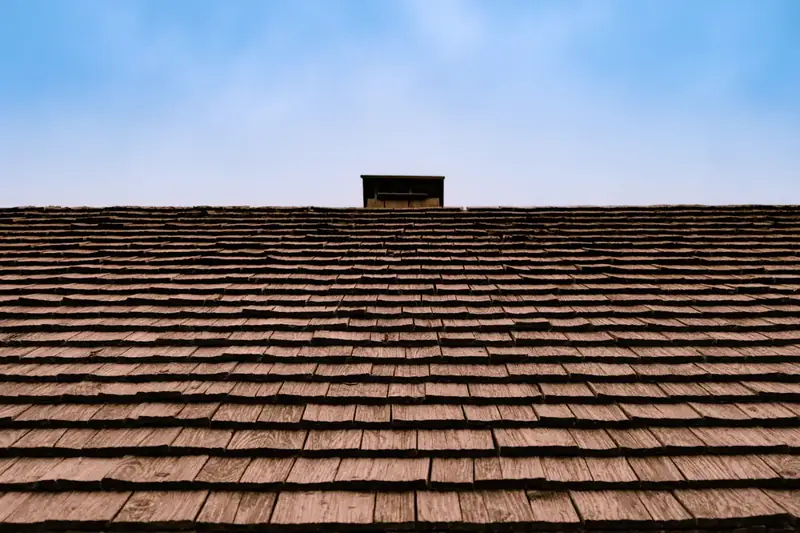 Weathered brown cedar shake roof with a chimney at the ridge