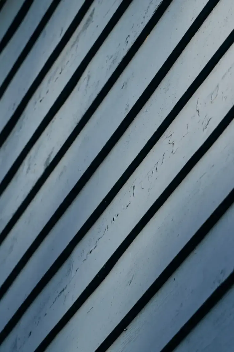 Close view of grey-blue painted lap boards running at a steep angle