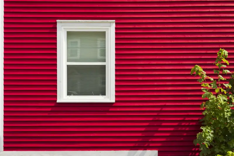 Red horizontal lap siding around a white-trimmed window